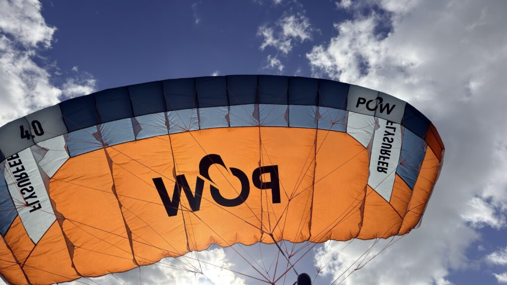 Used Flysurfer POW 4.0m parawing flying, orange canopy against a blue sky